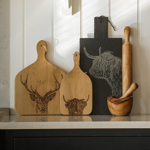 Natural wood cutting board with detailed engraved deer head design paired with olive wood rolling pin for rolling dough