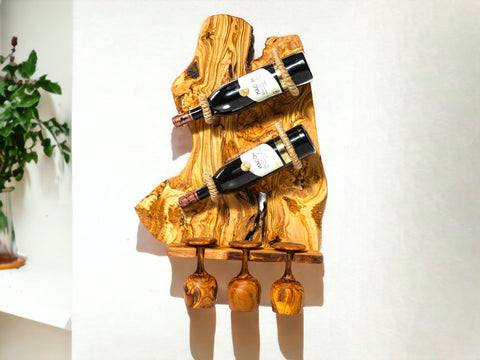 A rustic olive wood bottle holder with natural grain holds two dark wine bottles with rope and three wooden goblet holders below