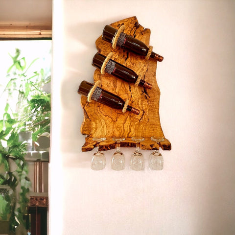 Olive wood rustic bottle holder with three dark wine bottles secured by rope and four clear stemmed glasses hanging below