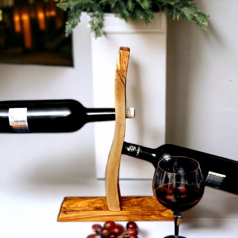 A sleek olive wood bottle holder with a curved design and natural grain perfect for wine or barware gifts