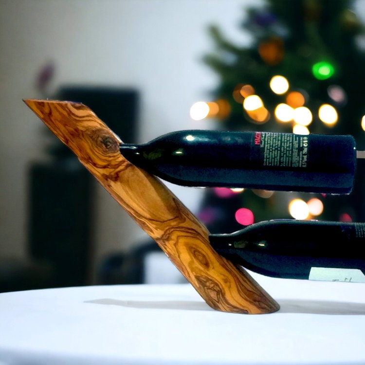 A sleek v-shaped olive wood bottle holder with natural grain and warm golden brown finish ideal for wine bottles