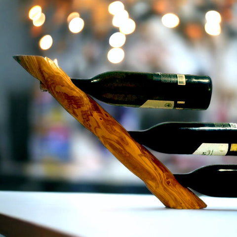 A sleek olive wood wave bottle holder with warm amber and reddish brown grain perfect for barware and gifts