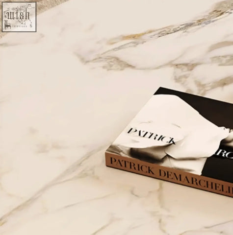 A sleek hardcover book with gold lettering on its spine resting on a white nesting coffee table set