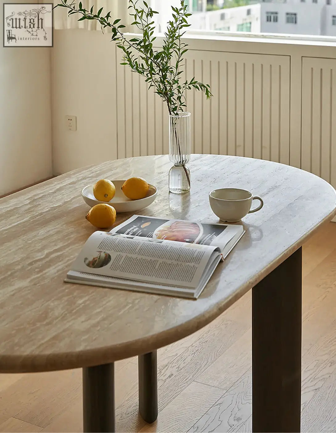 A sleek oval dining table with travertin marble top and dark solid wood legs perfect for stylish dining rooms
