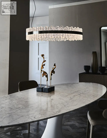 A modern oval dining table with marble top and sleek black chandelier with clear crystals in dining room setting
