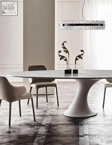 A sleek omer oval dining table with a polished white marble top and minimalist pedestal base for dining room use