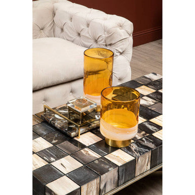 Two amber glass candle holders with frosted base on marble tray next to ophelia 3 seat beige velvet sofa