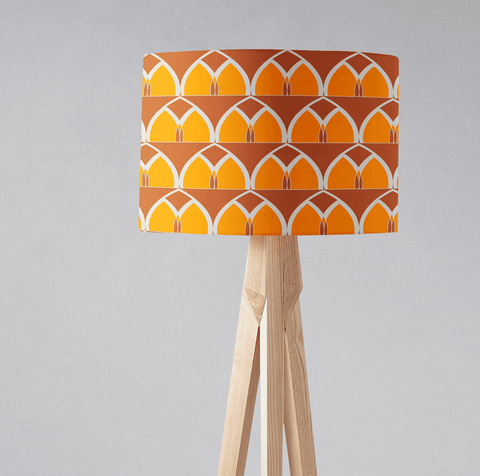 Orange and yellow geometric arches table lamp with a cylindrical fabric shade and light wood tripod floor lamp base