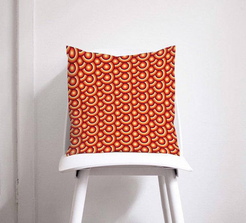 Orange cushion throw pillow with 70s retro circles design featuring concentric circles in red and orange shades