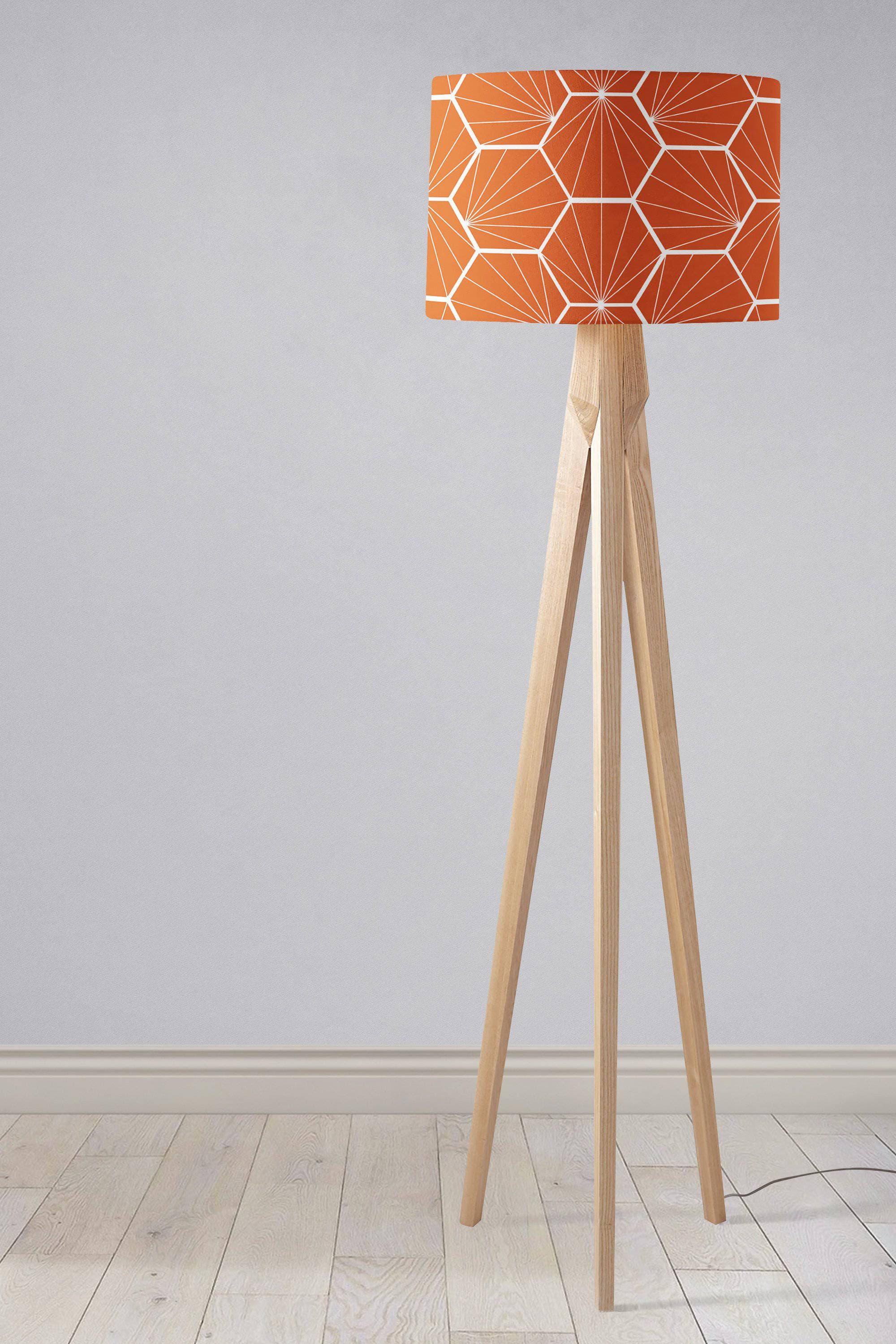 Orange lampshade with white hexagon pattern on a light wood tripod base table lamp design