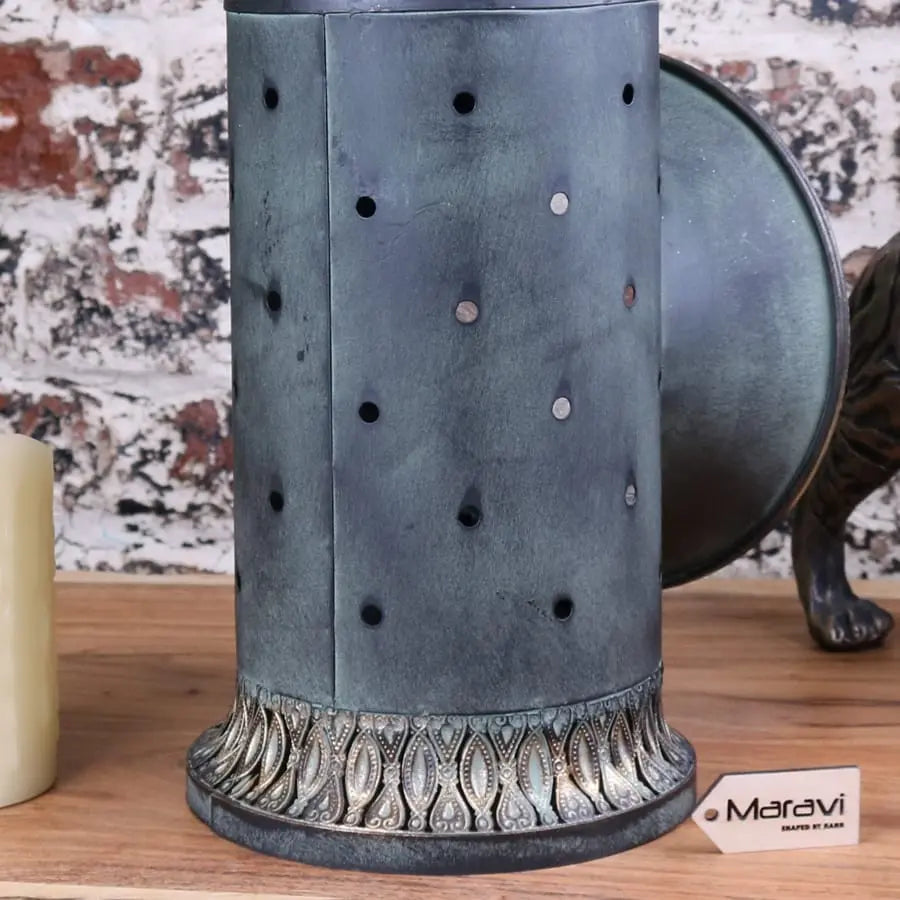 Antique metal candle holder with patina finish and decorative perforations in orchha vintage style railway lantern