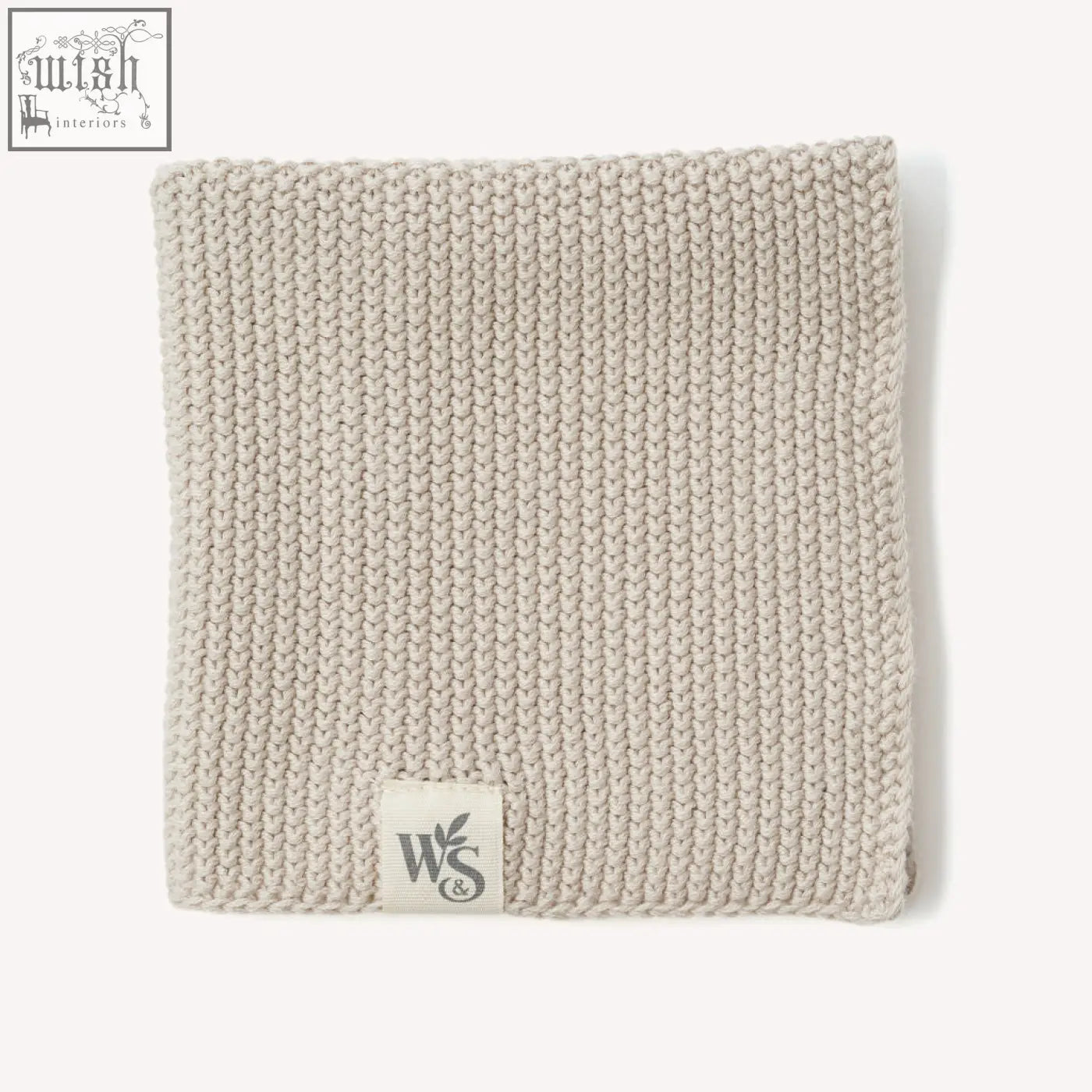 A soft beige knitted organic cotton dishcloth with a ribbed texture and a small white ws logo label