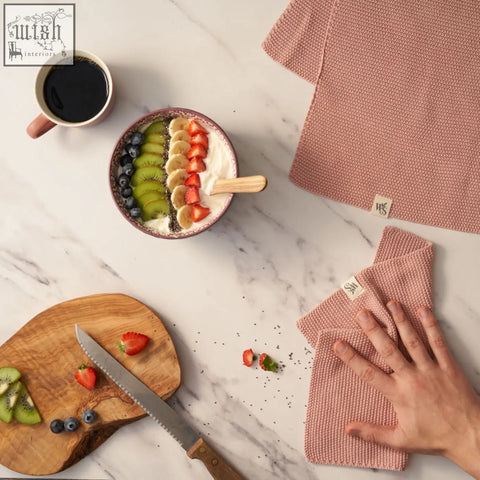 Pink textured knitted organic cotton dishcloth with woven pattern and small brand tag for kitchen use