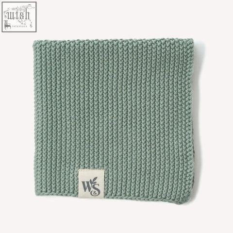 A soft sage green knitted organic cotton dishcloth with a ribbed pattern and a white w&s label