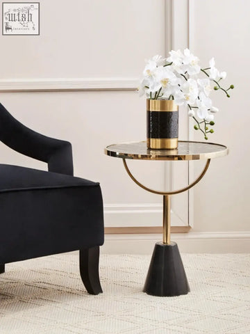 Gold and black textured cylindrical vase with white orchids on oria black glass marble base side table