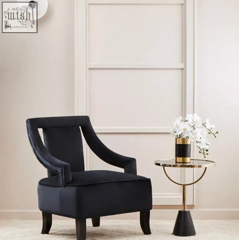 Navy blue velvet armchair with curved wooden legs beside an oria black glass marble base side table
