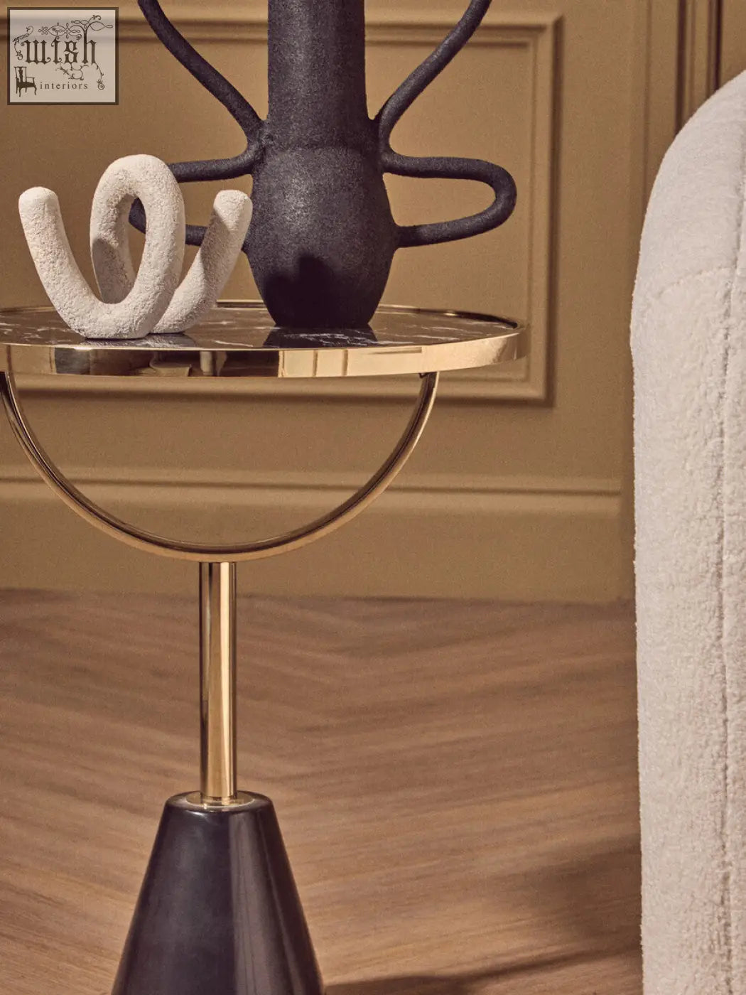 A sleek oria black glass side table with a polished gold top and marble base supported by a slim brass stem