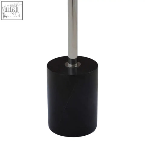 Black cylindrical toilet brush holder with polished chrome handle next to oria black marble end table with stainless steel base