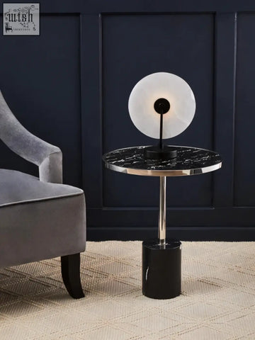 Oria black marble end table with sleek black marble top and stainless steel pedestal holding a circular white lamp