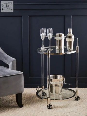 Silver toned oria round 2 tier drinks trolley with clear acrylic legs glass shelves polished metal frame and caster wheels