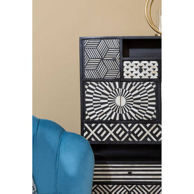Black and white geometric-patterned cabinet with a modern artistic design next to blue velvet scalloped curved chair with wood legs