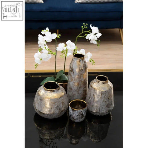 Set of four small grey and gold ceramic planters in metallic distressed finish on reflective surface