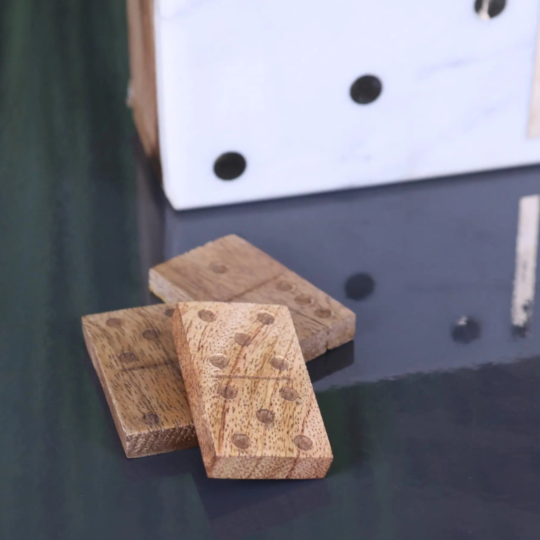 Light brown wooden dominoes with natural grain and black dots in the osian marble lid luxury dominoes set