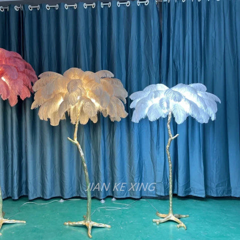 Three ornamental ostrich feather floor lamps in pink cream and white on gold tree-like stands for living room decor