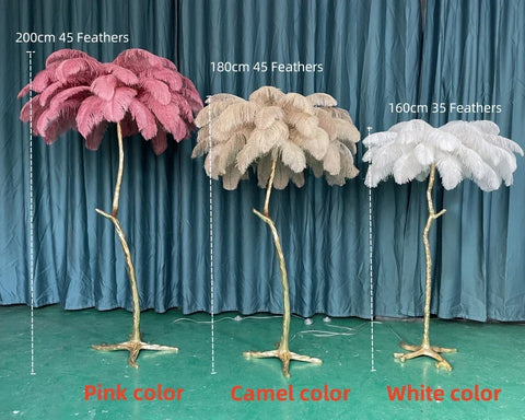 Three ostrich feather floor lamps in pink camel and white with gold metal stems perfect for living room lighting