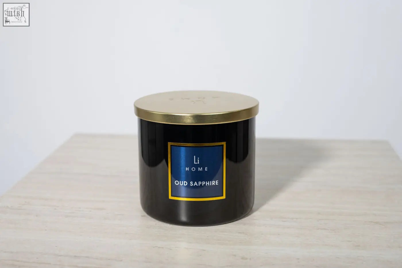 Black cylindrical oud sapphire luxury candle with gold lid and blue label from li home large candle collection