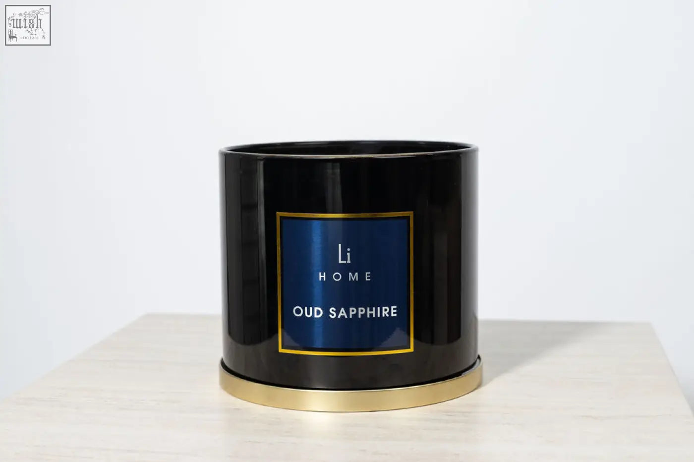 Black cylindrical 3 wick luxury candle with gold rim and navy blue li home label from large candle collection