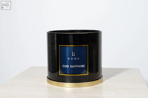 Black cylindrical 3 wick luxury candle with gold rim and navy blue li home label from large candle collection