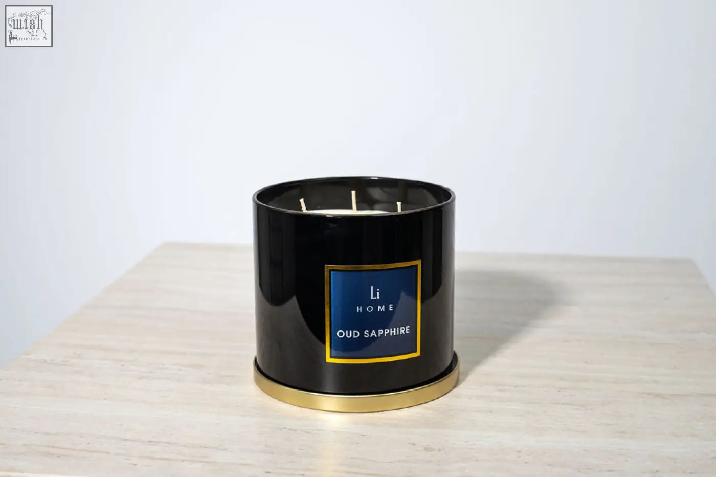 Black cylindrical 3 wick luxury candle with gold trim and blue label from li home oud sapphire in large candle collection