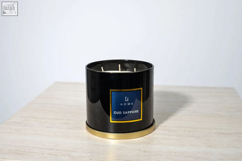Black cylindrical 3 wick luxury candle with gold trim and blue label from li home oud sapphire in large candle collection