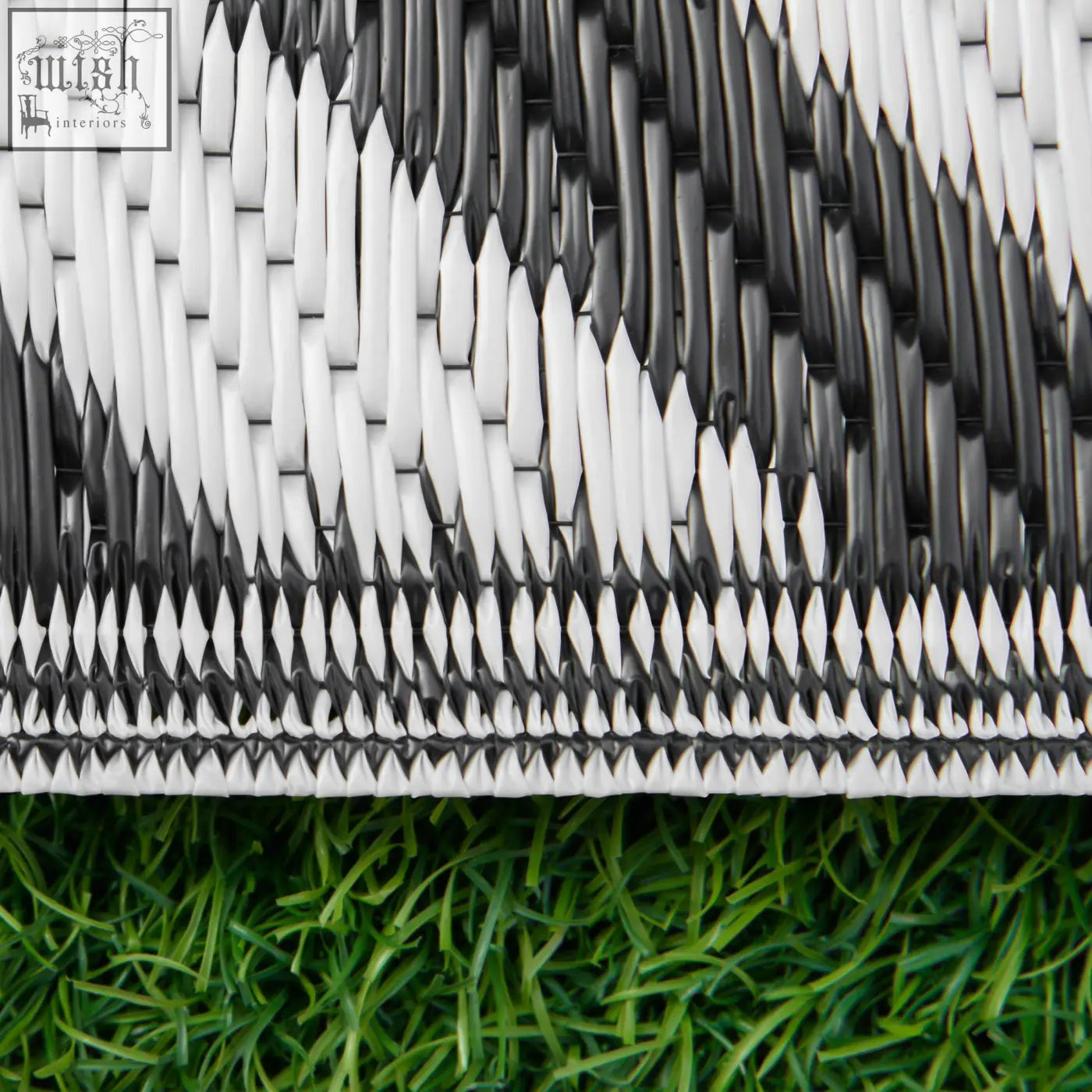 Black and white outdoor rug made of plastic straw with a textured pattern perfect for road tour and camping use