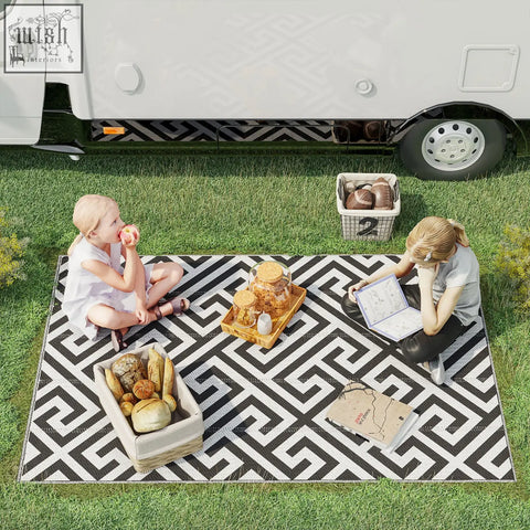 Black and white geometric patterned outdoor rug made of plastic straw perfect for road tour picnic or camping use