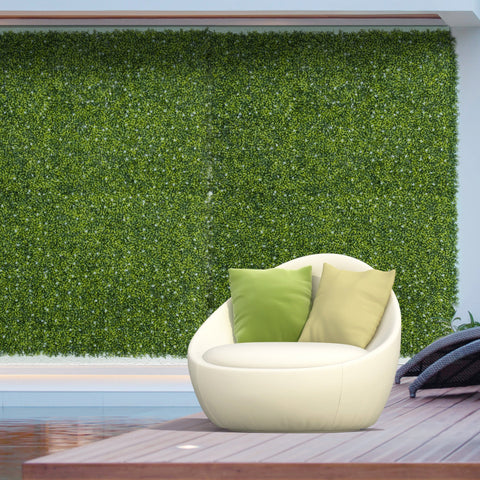 Cream-colored modern egg-shaped lounge chair with two green pillows beside milan grass 50cm x 50cm wall panel backdrop
