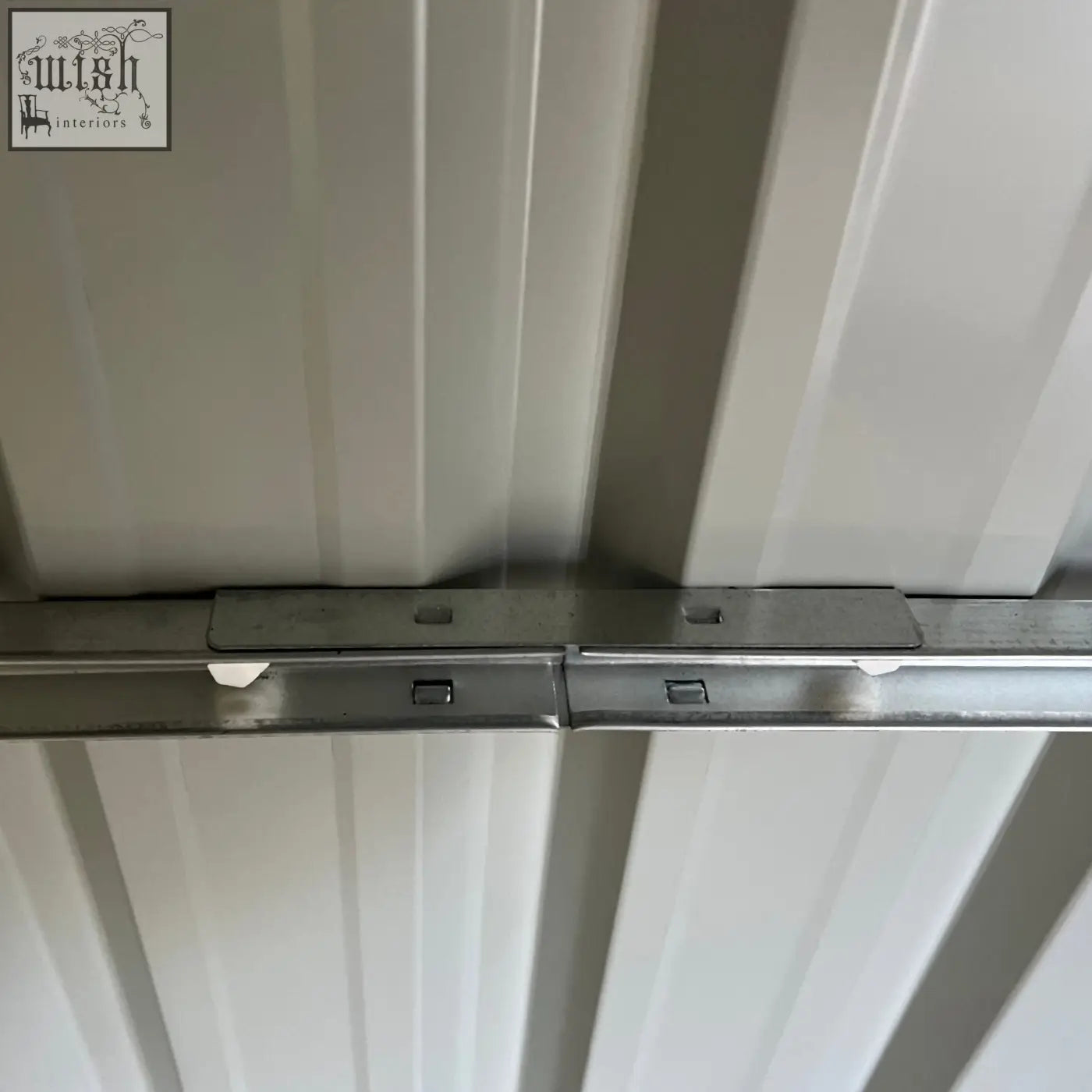 Silver metal track with white clips and brackets for mounting on the back of an outsunny grey outdoor garden storage shed