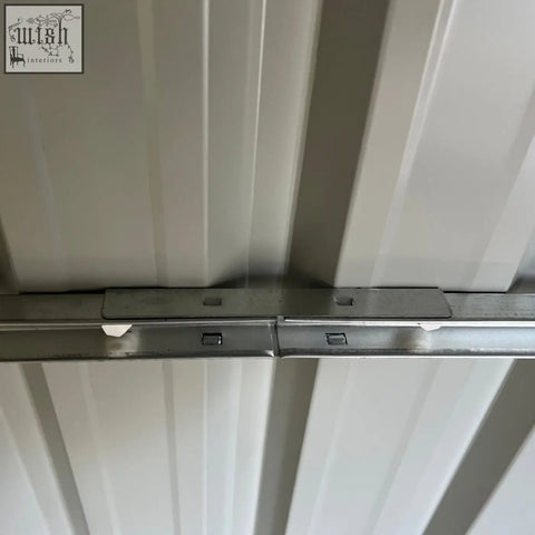 Silver metal track with white clips and brackets for mounting on the back of an outsunny grey outdoor garden storage shed