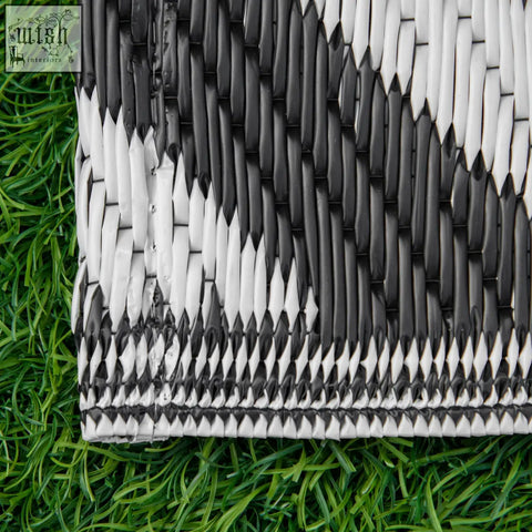Black and white woven outdoor rug with geometric pattern made of plastic straw for road tour and camping use