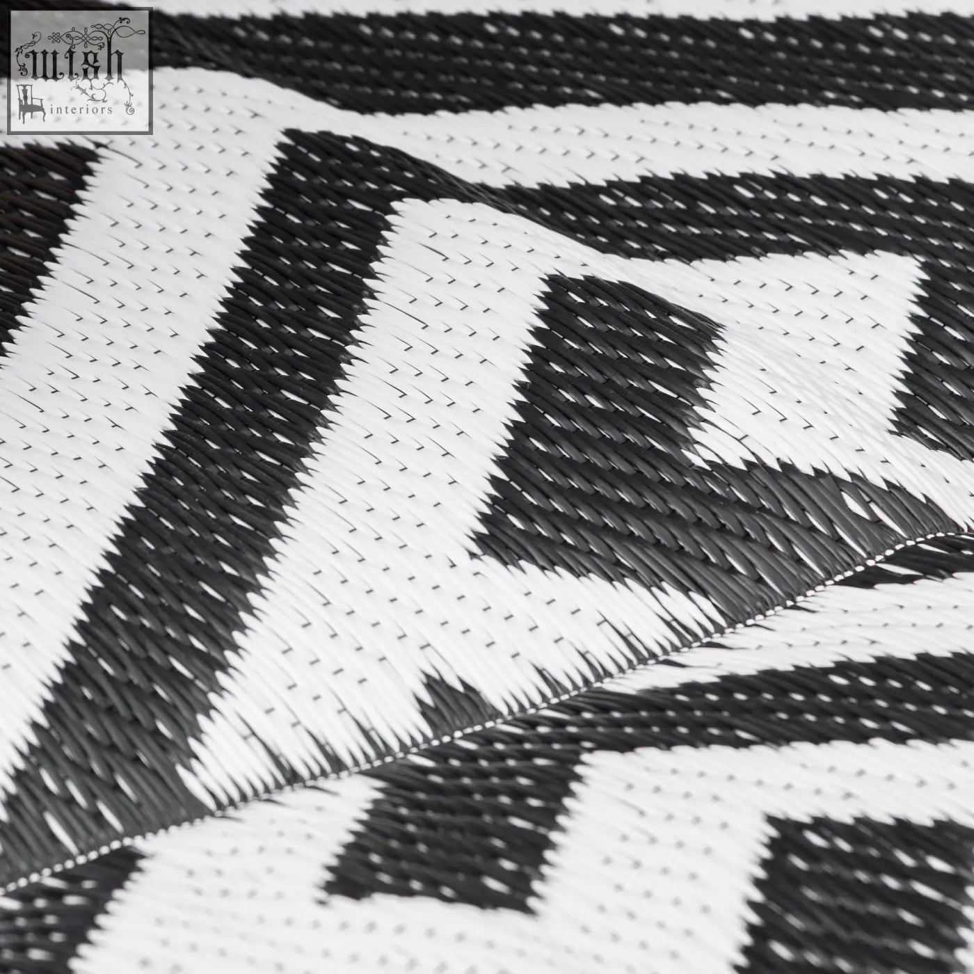 Black and white woven outdoor rug with geometric zigzag pattern made of plastic straw perfect for road tour use