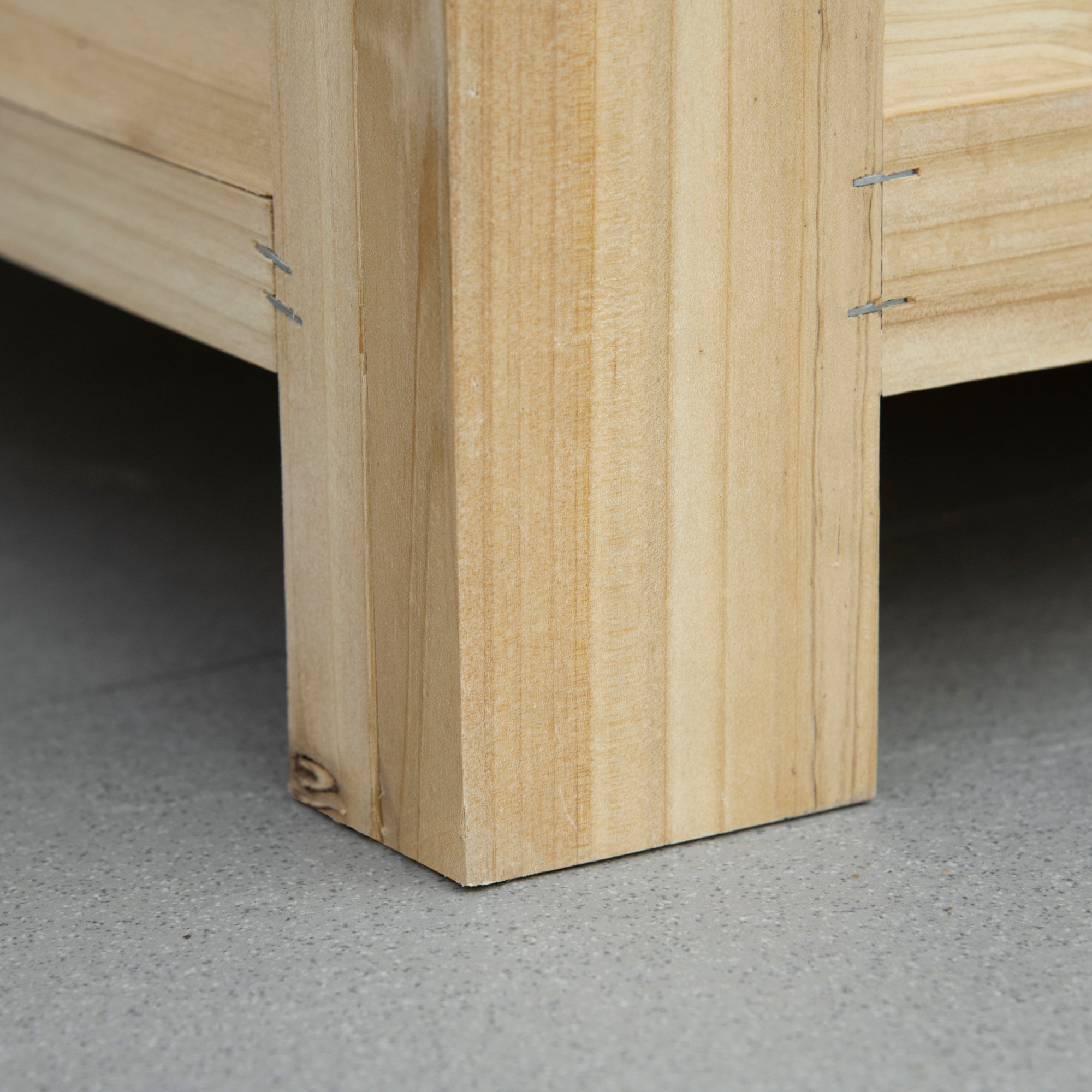 Light-colored wooden leg of outsunny outdoor storage box with galvanised metal fasteners for garden use