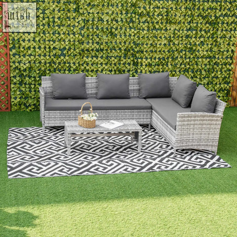Gray wicker outdoor sectional sofa with dark gray cushions next to outsunny black and white reversible plastic straw outdoor rug for road tour
