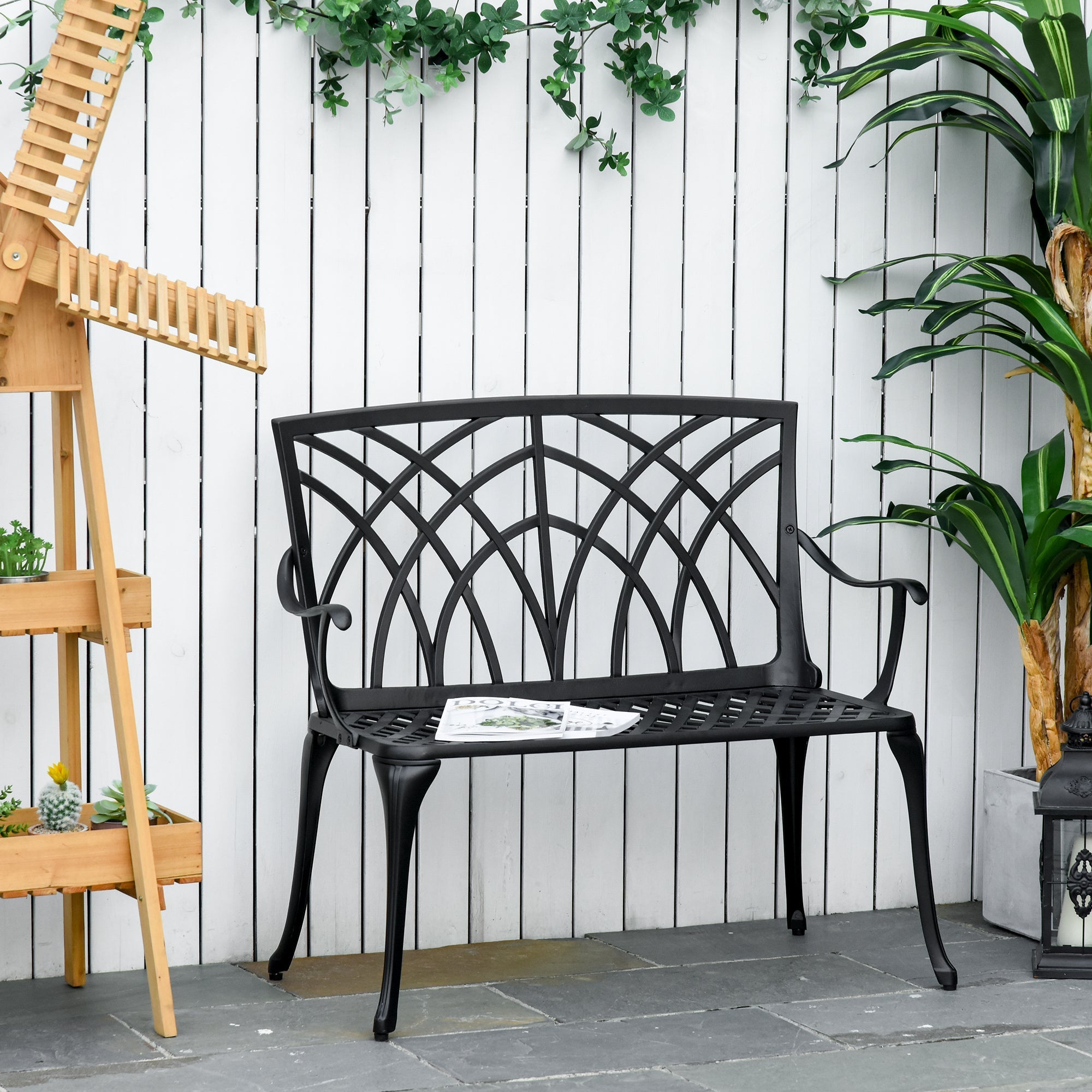 Black cast aluminium garden bench with curved line design and intricate arched back for outdoor patio use