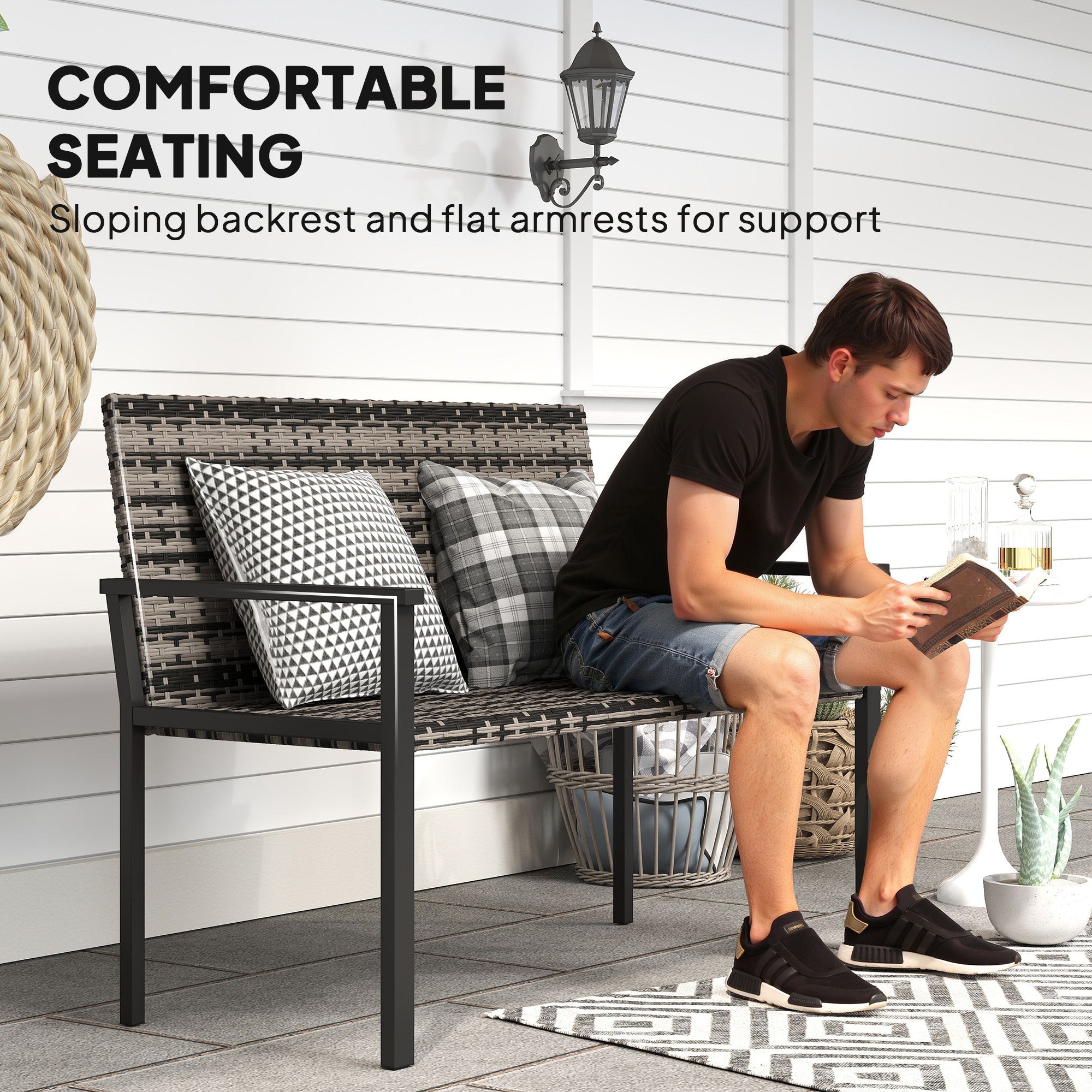 Black wicker two-seater garden bench with steel frame and patterned throw pillows for patio or park use