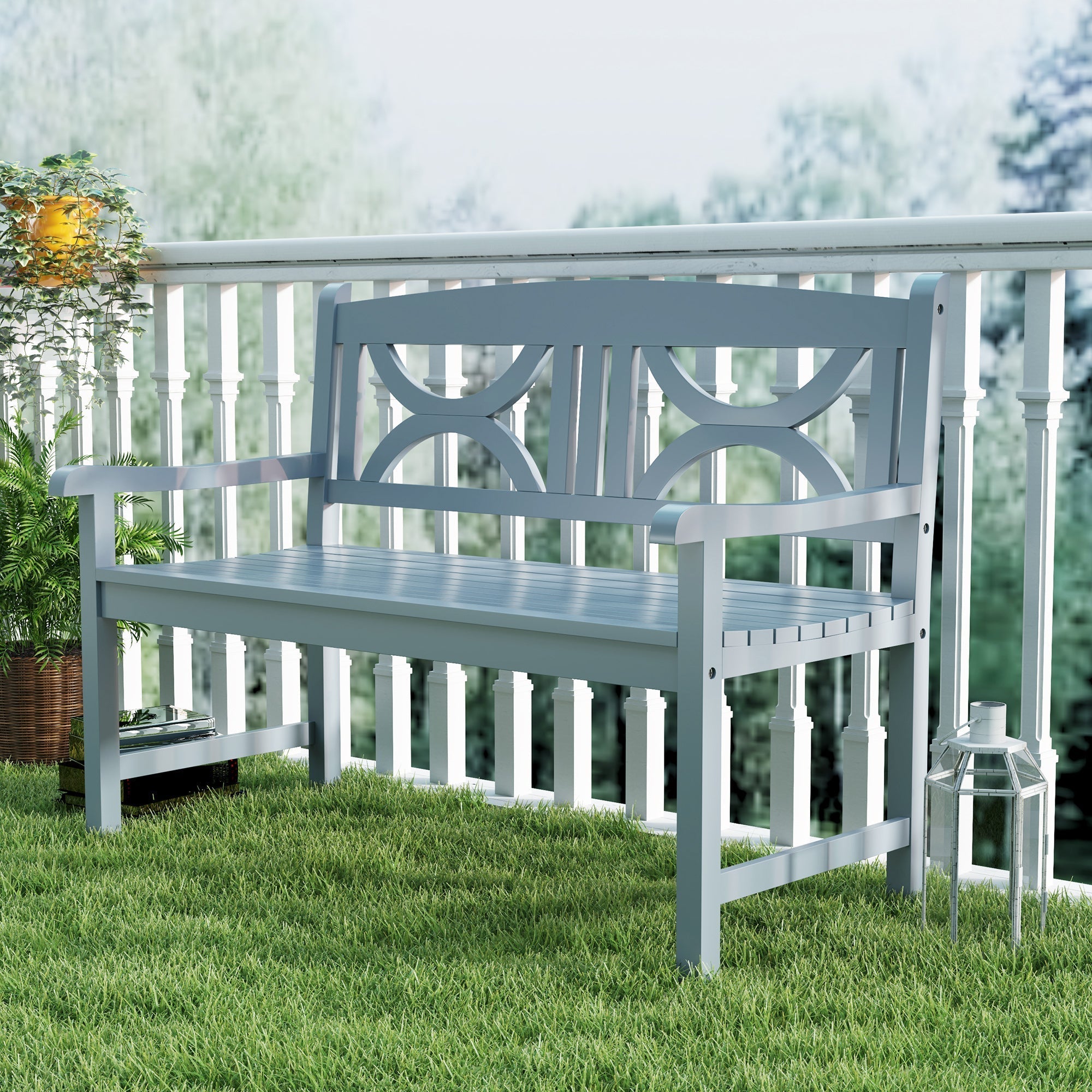 Gray poplar wood garden bench with decorative backrest and armrests on grass near white railing outdoors