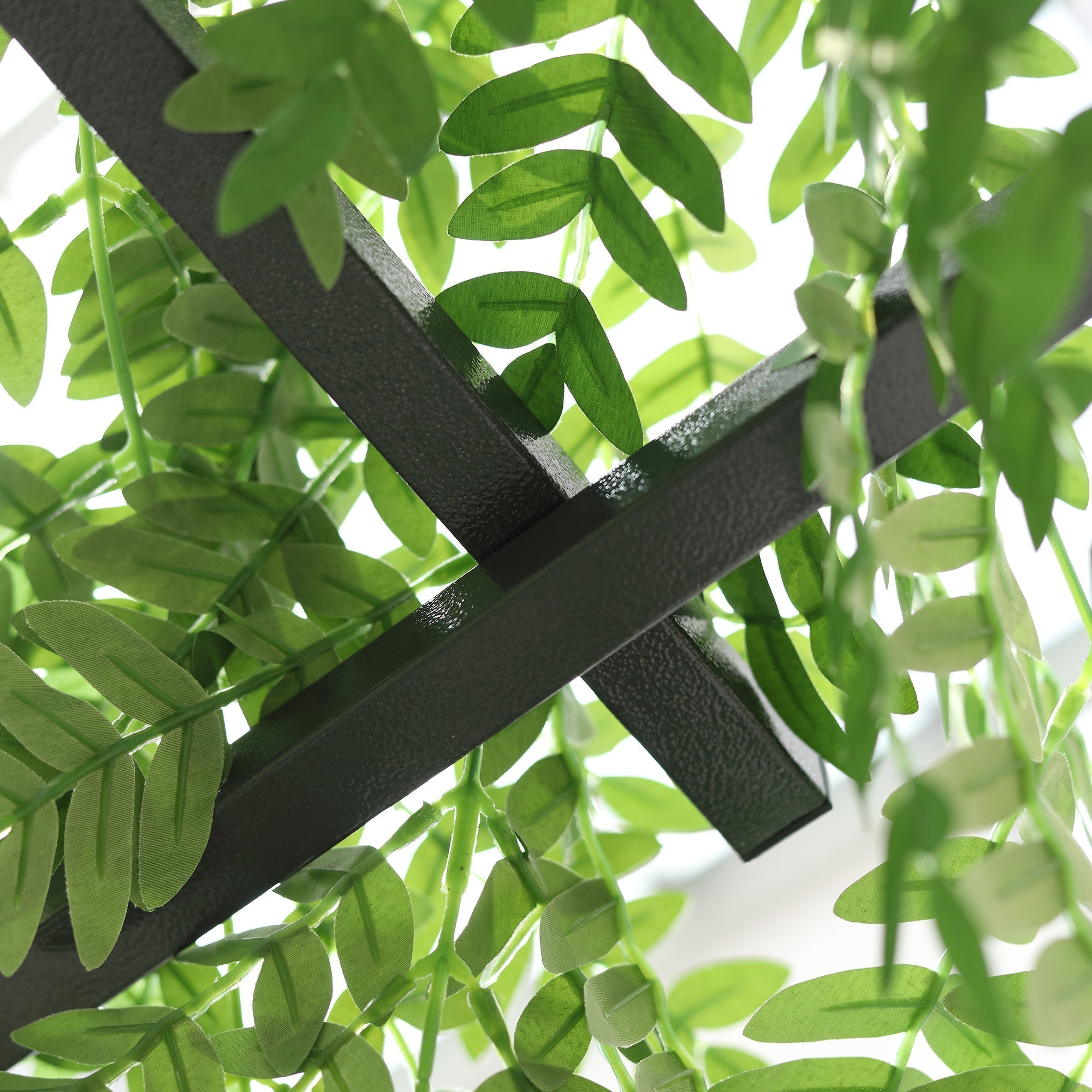 Black metal garden trellis with elegant scrollwork and artificial green leaves adds rustic charm for climbing vines and weddings