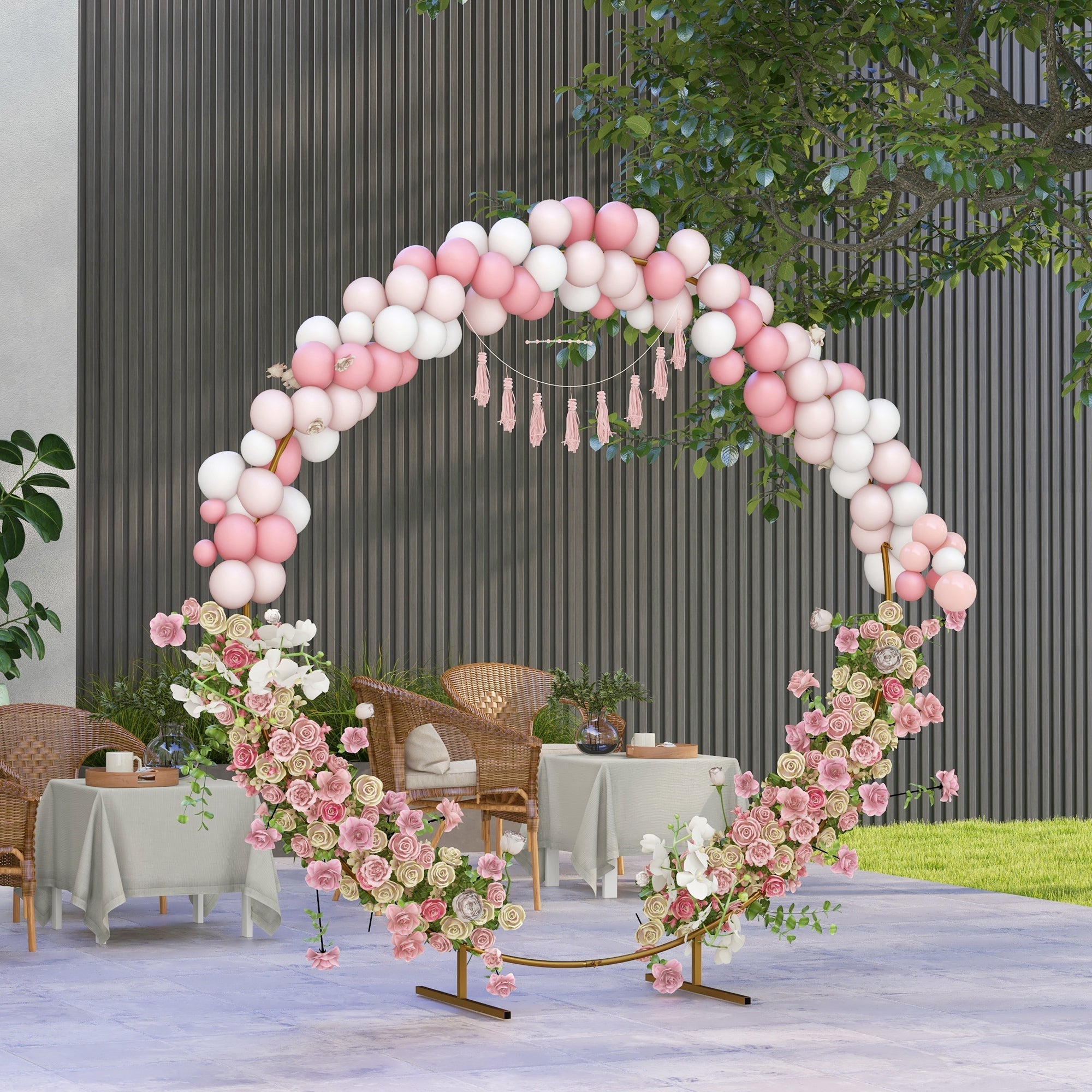 Decorative pink and white balloon arch with floral and tassel accents on a gold tone wedding arch backdrop stand