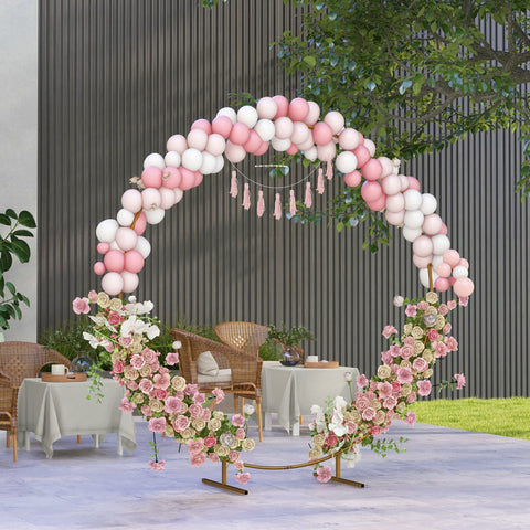 Decorative pink and white balloon arch with floral and tassel accents on a gold tone wedding arch backdrop stand
