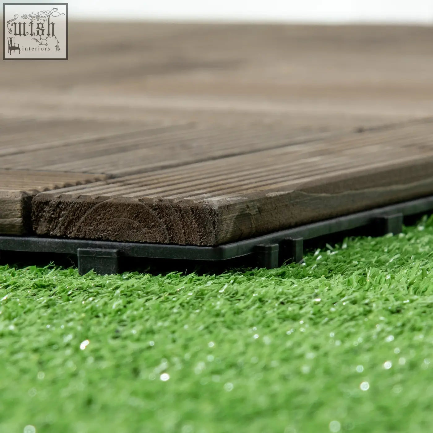 Dark brown solid wood decking tiles with black pvc bottoms and e3 8e a1 edges on artificial green grass
